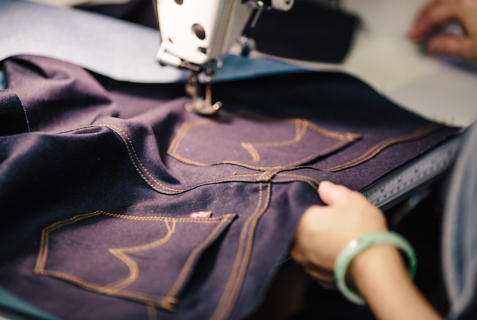 Woman Hand Shows A Large Hole On Pant Leg Of A Blue Jeans Folded In Half  Jeans Are Prepared For Cutting Out For Making Denim Shorts With Scissors  Pins And Tailor Tape