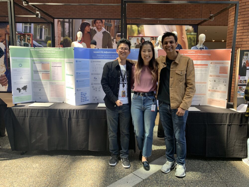 three interns standing in front of a table with their presentation posters