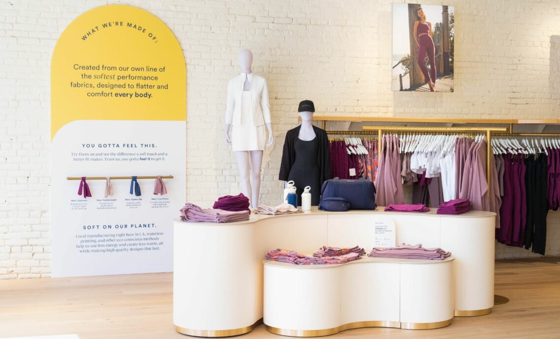 The interior of a Beyond Yoga® store featuring products folded on a white center display.