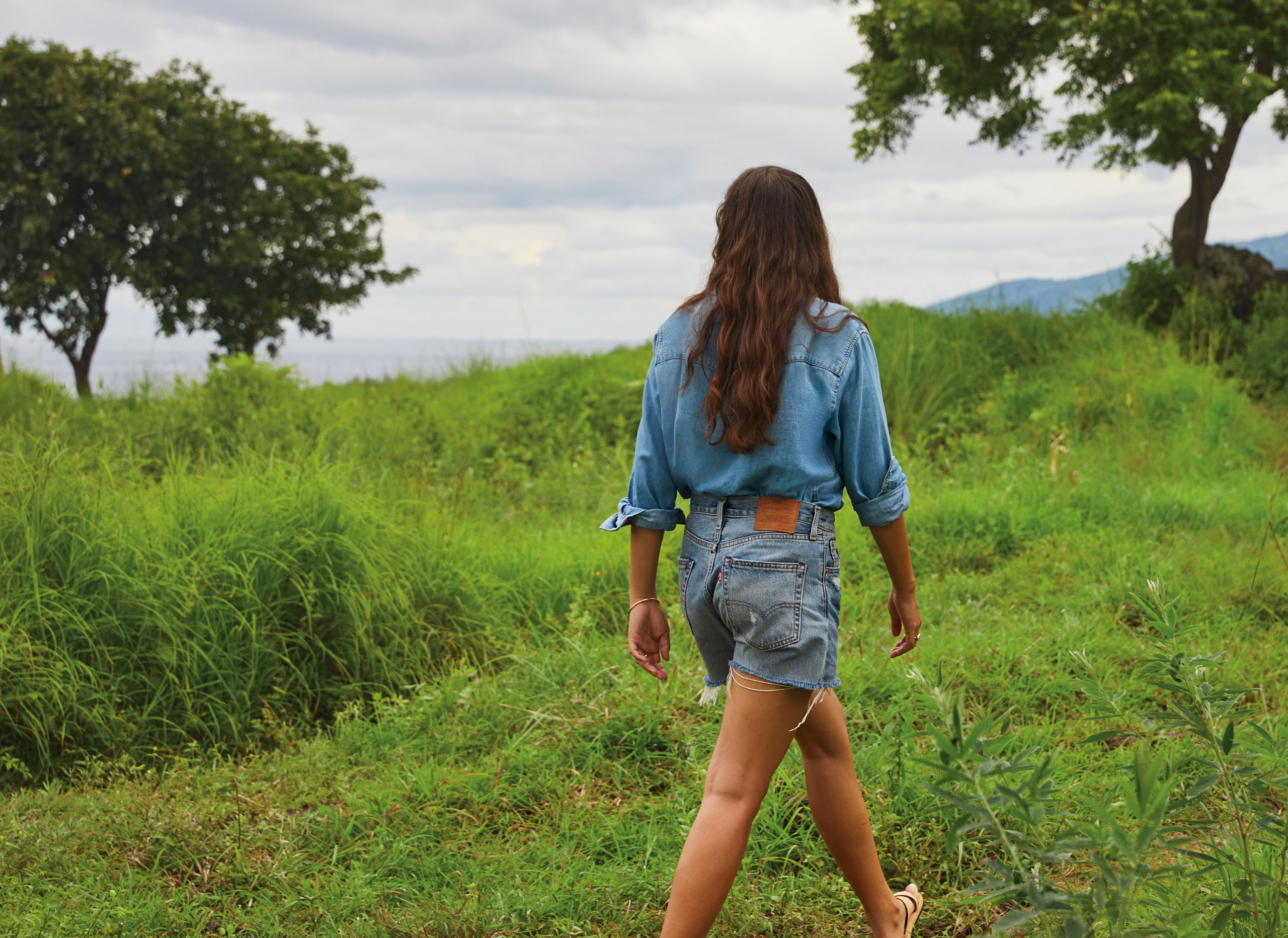 woman walking in grassy field wearing Levi's® denim shorts