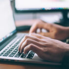 hands typing on an Apple laptop keyboard