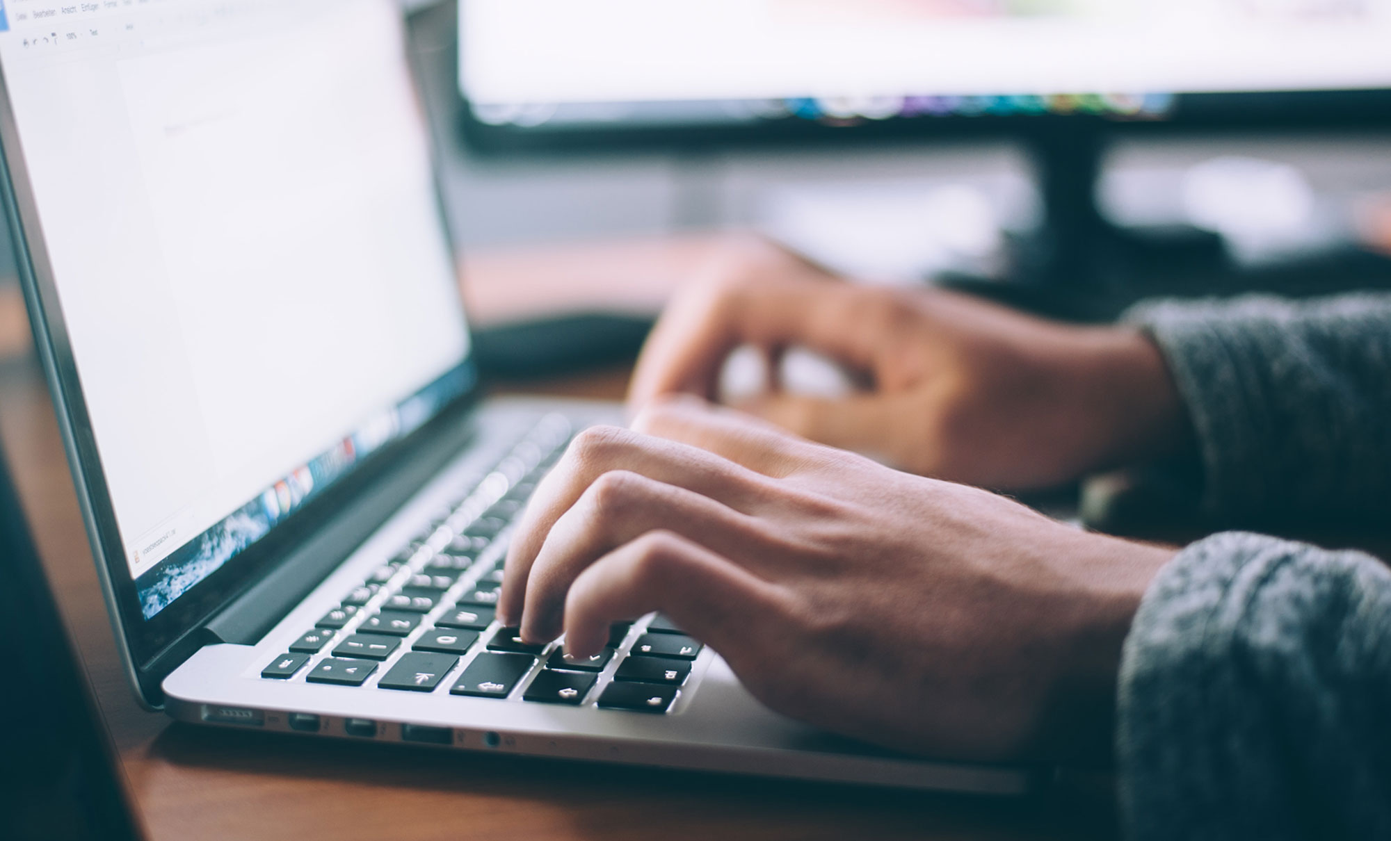 hands typing on an Apple laptop keyboard