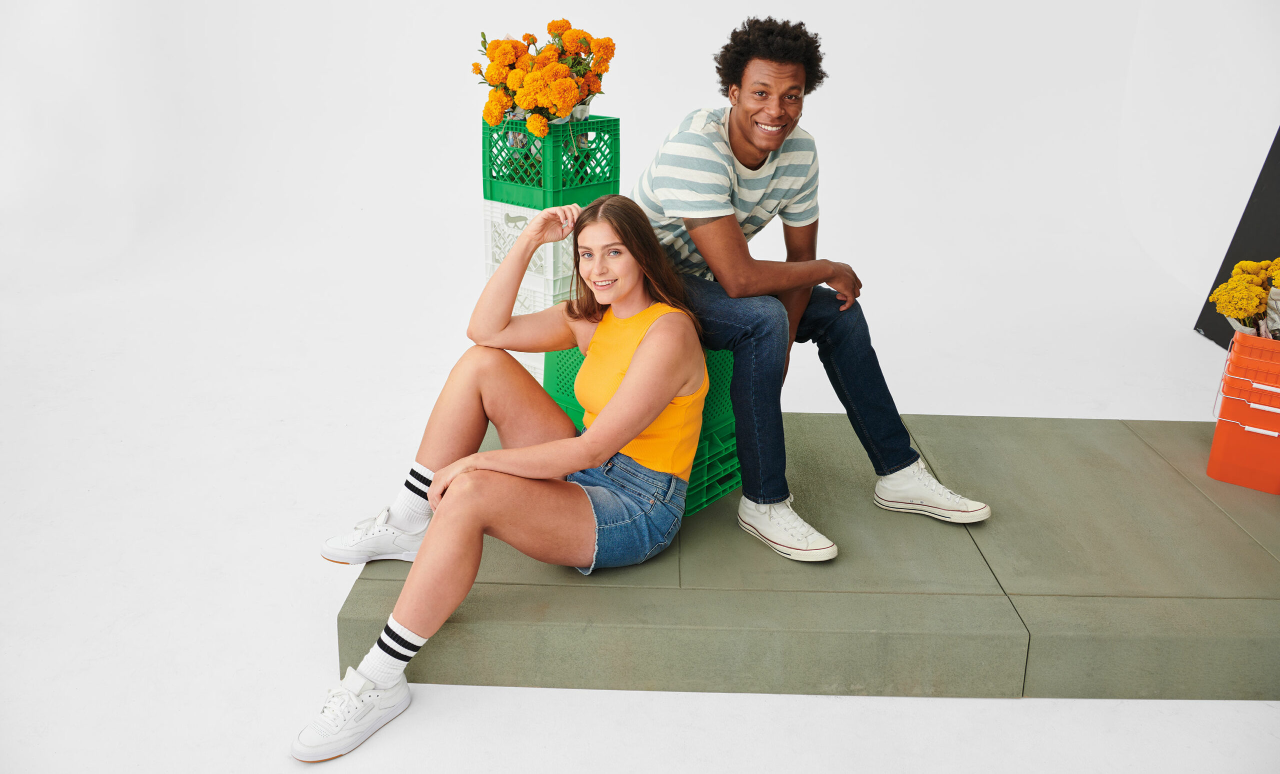 Women in Levi's® jean shorts and man in Levi's® jeans sitting down and posing in product.