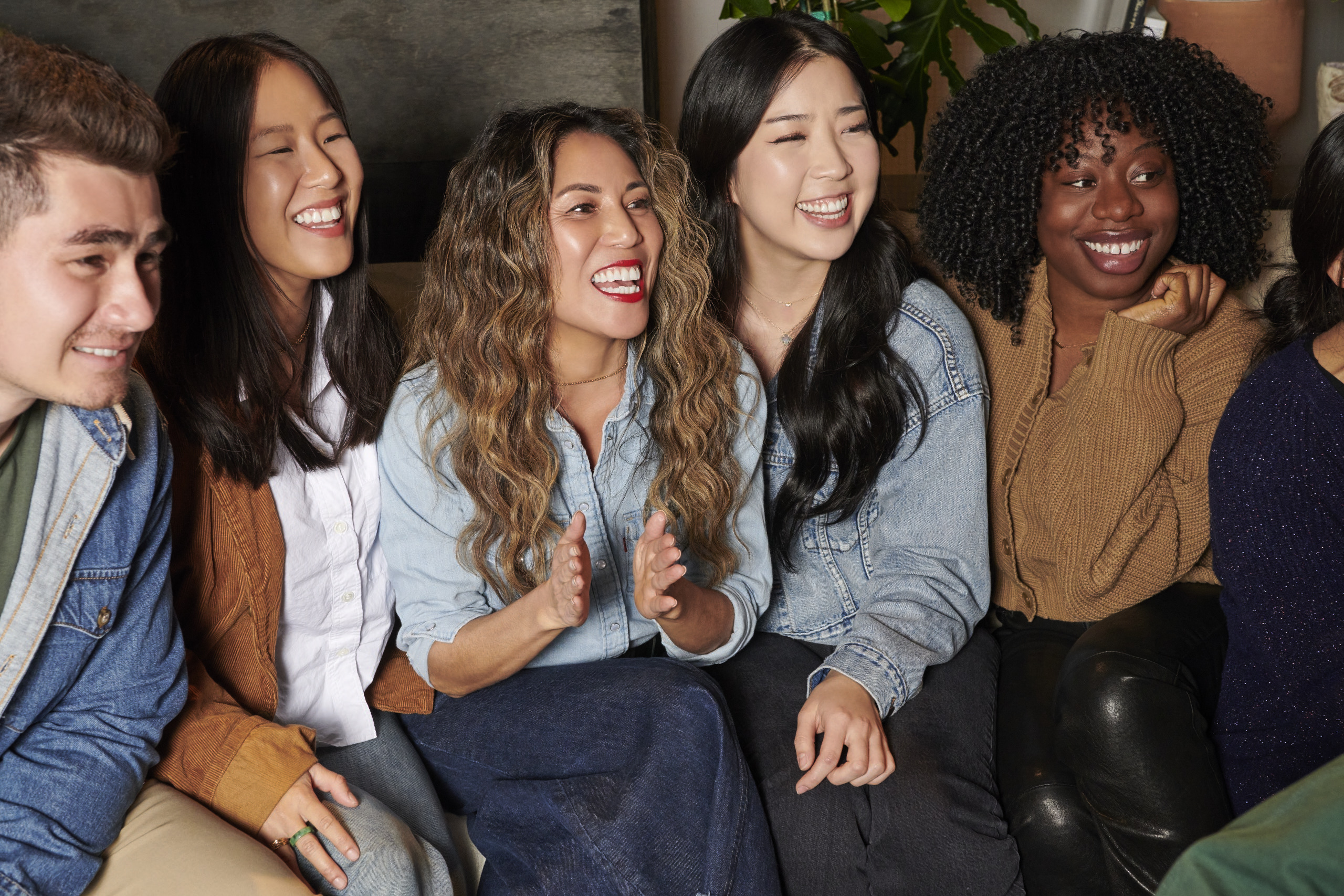 A group of LS&Co. employees sit on the couch, laugh and look off to the right.