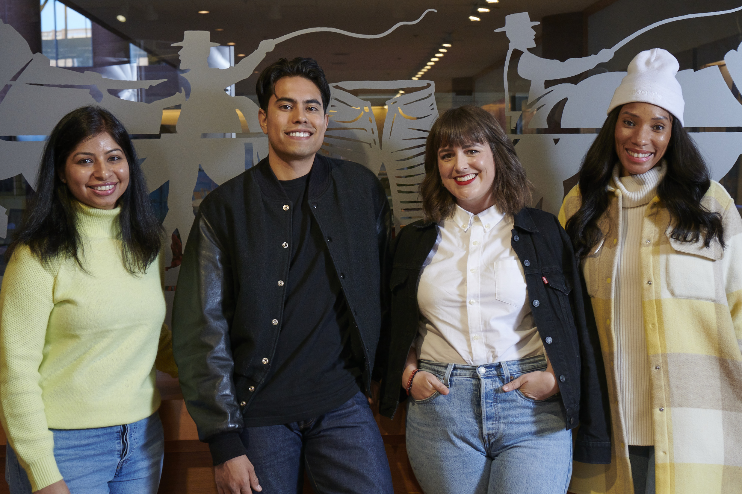 Four LS&Co. employees stand against a wall smiling