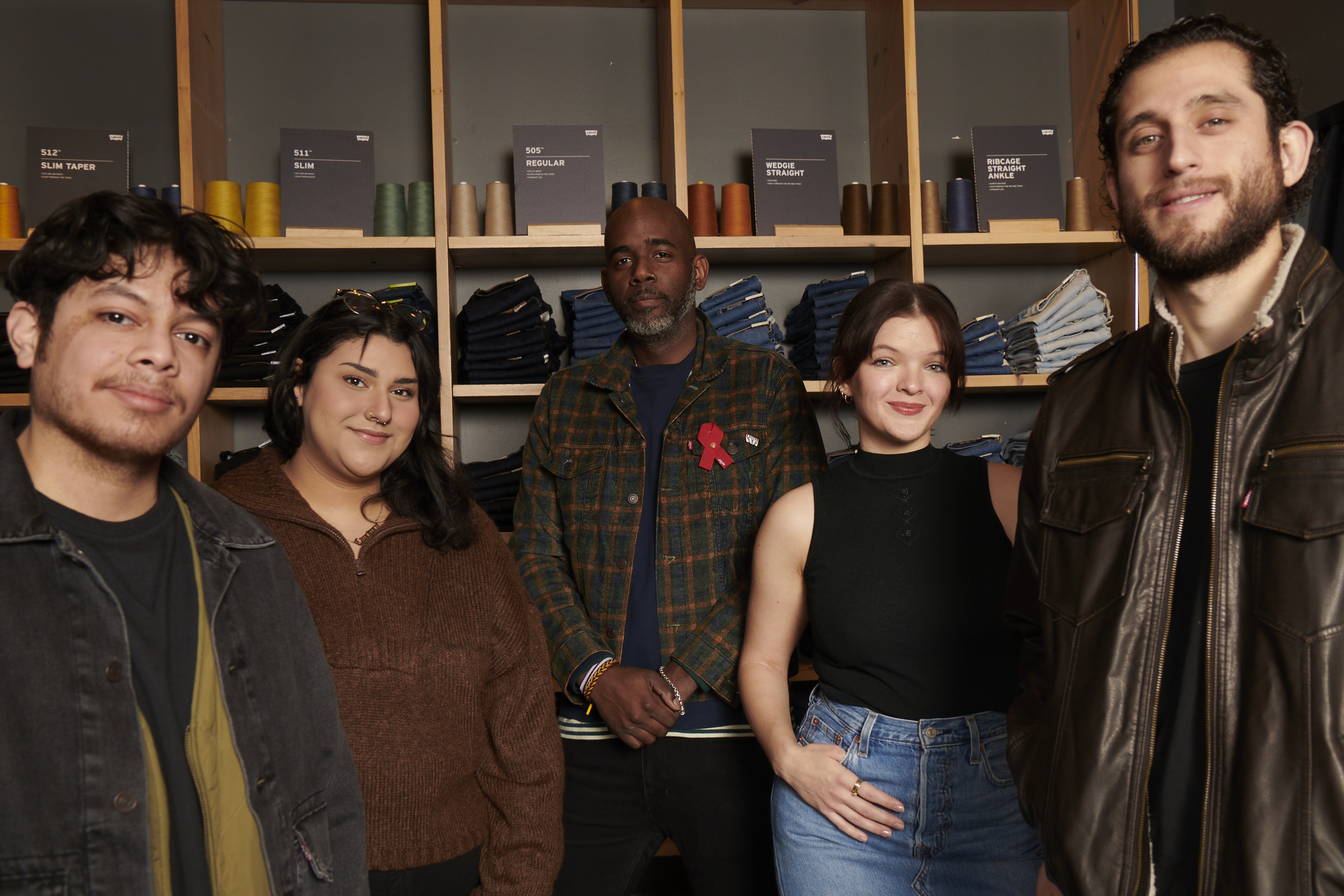 Five LS&Co. employees stand against a wall of stacked Levi's® jeans