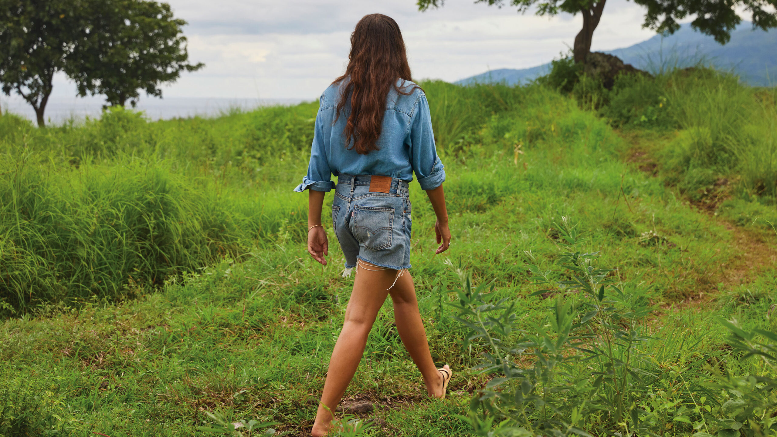 woman walking in grassy field wearing Levi's® denim shorts