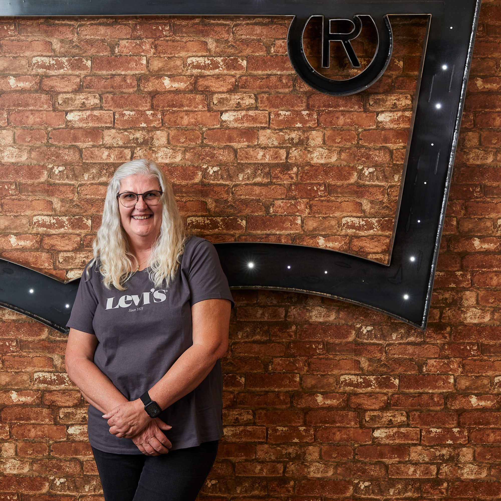 An LS&Co. employee leans against a brick wall and a large Levi's® batwing logo.
