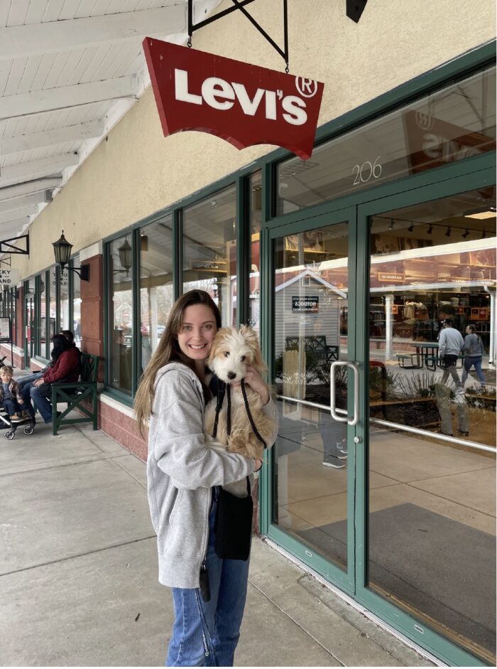 Sarah Keuver and her service dog in front of a Levi's store sign