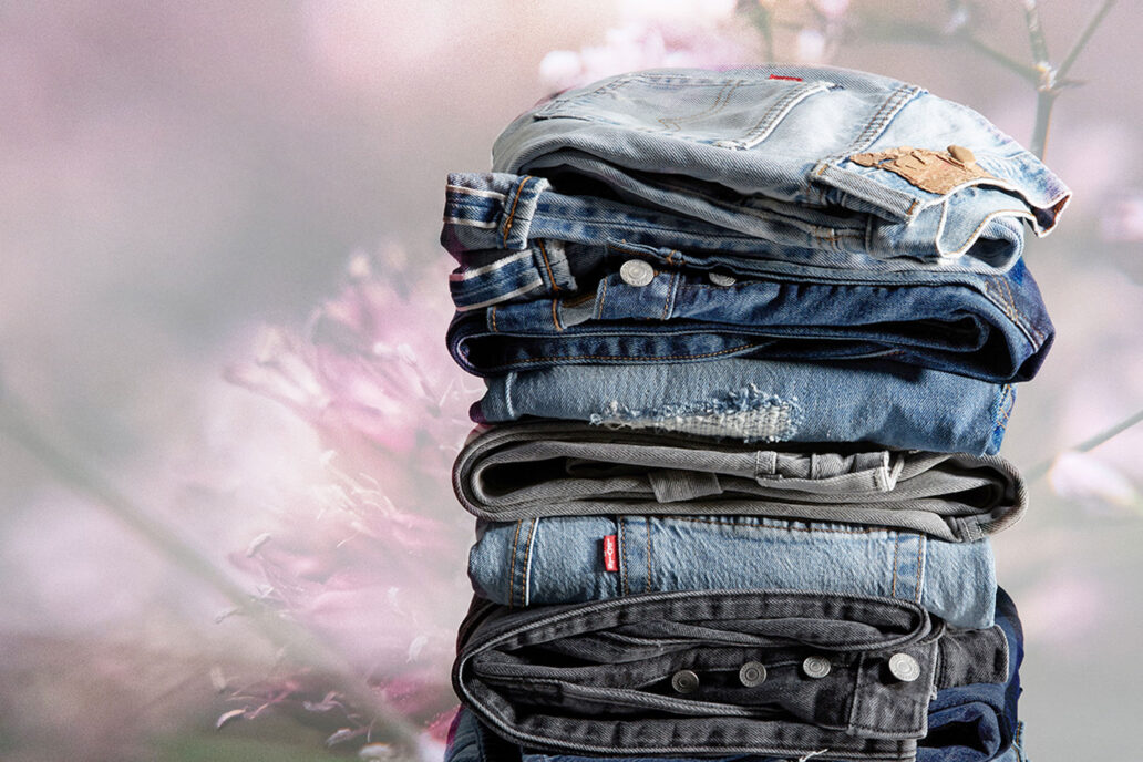 A stack of folded Levi's® denim jean sin various washes with a washed out floral background