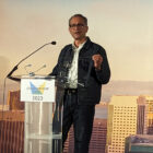 LS&Co. Chief Financial & Growth Officer Harmit Singh stands at a podium with a San Francisco skyline backdrop to accept the Larkin Street 2023 Hall of Fame Lifetime Achievement Award.