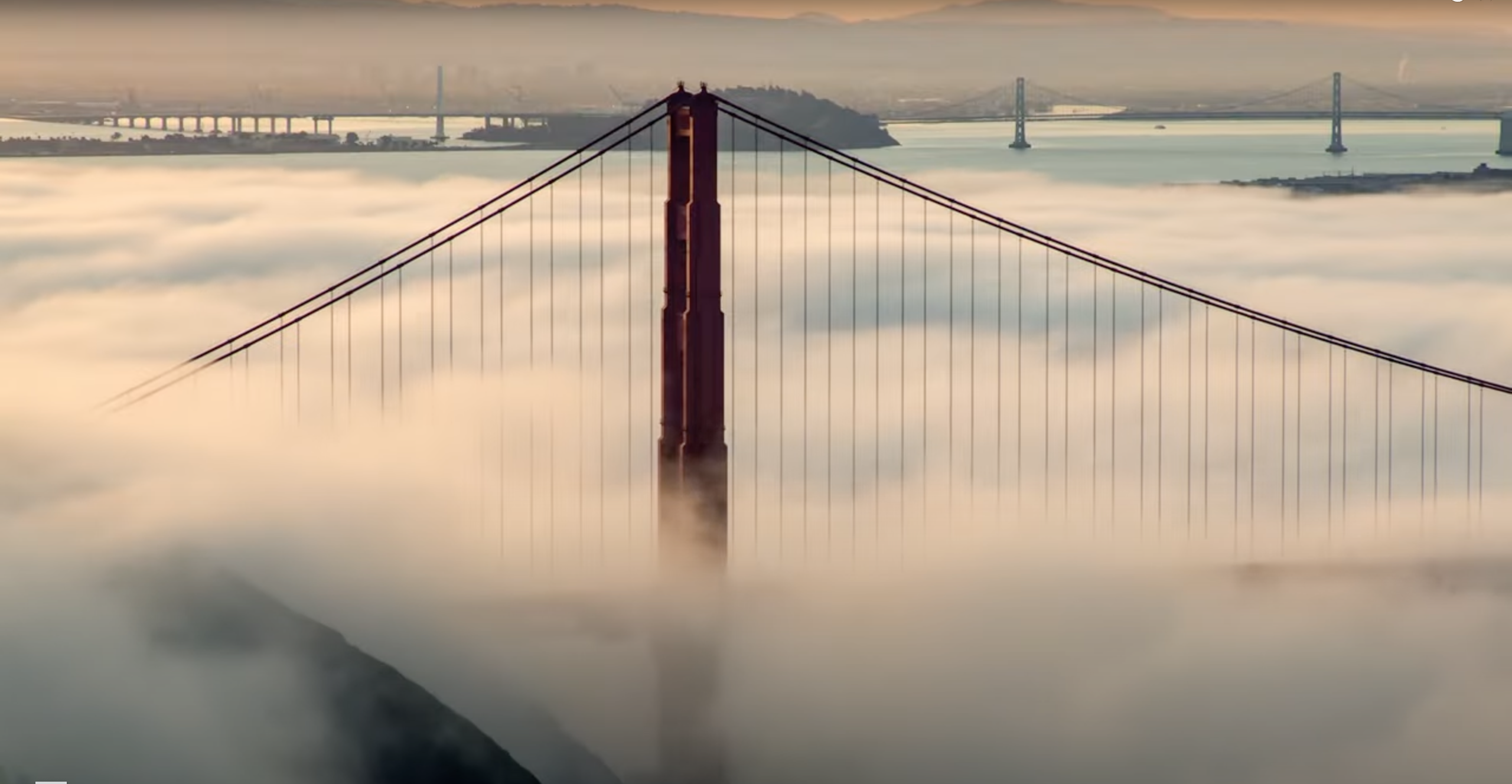 the top of the golden gate bridge peeks out through clouds