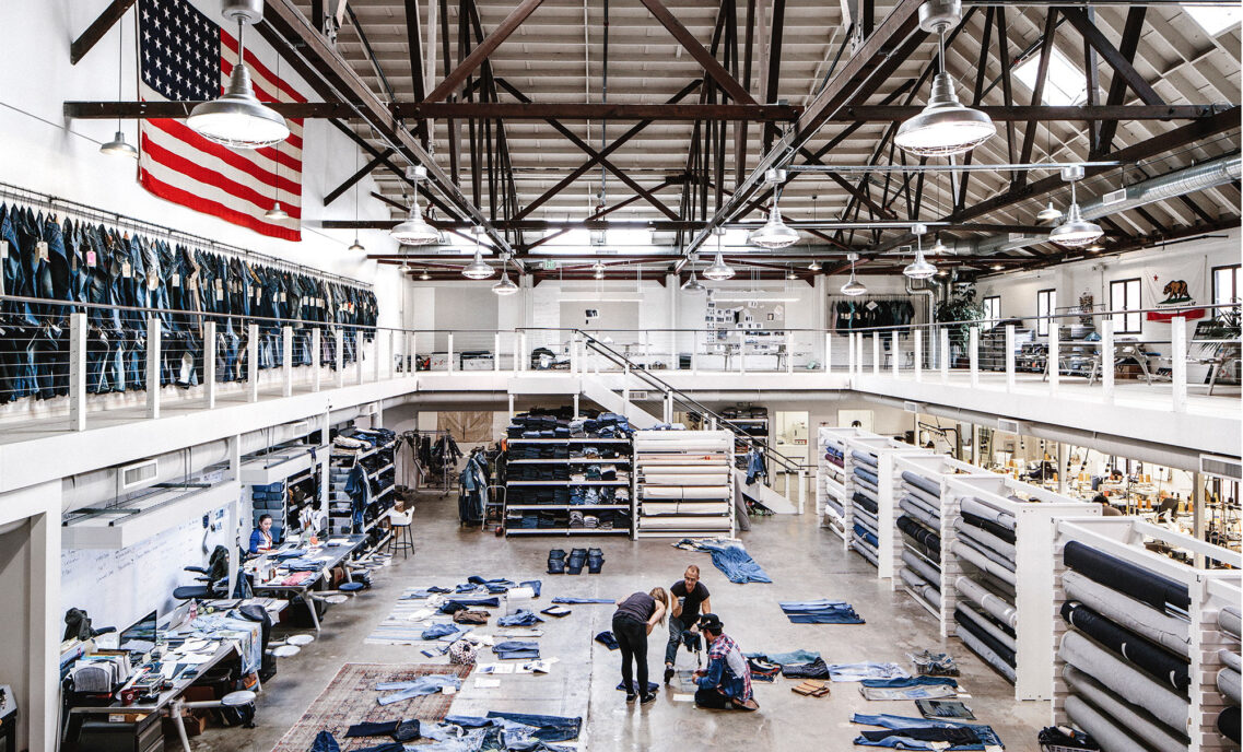 An interior shot of the LS&Co. Eureka Innovation Lab in San Francisco featuring piles of denim jean samples on the floor and employees looking through them.