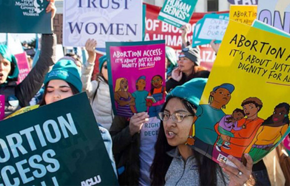 People gather holding signs advocating for reproductive rights and abortion access.