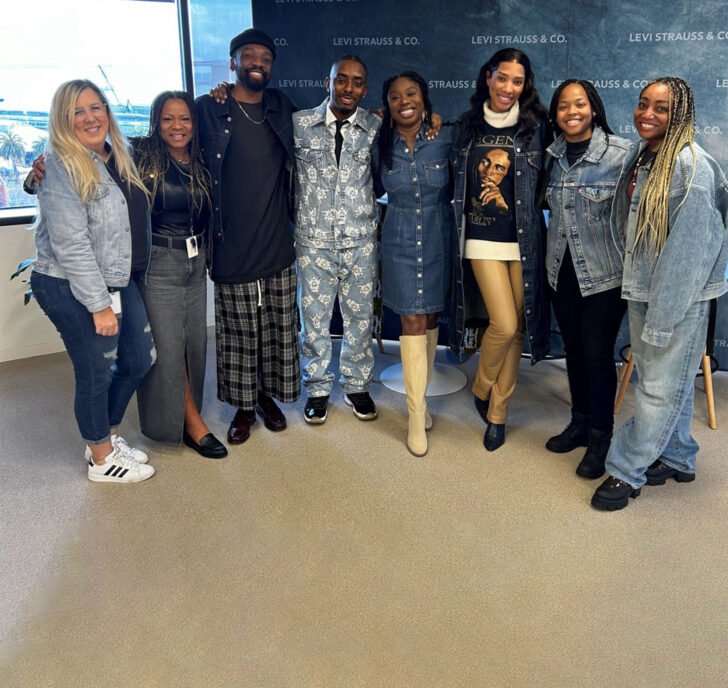 A group of eight LS&Co. employees pose at a Project Onyx ERG event against a blue background covered with a step and repeat of "Levi Strauss & Co." text