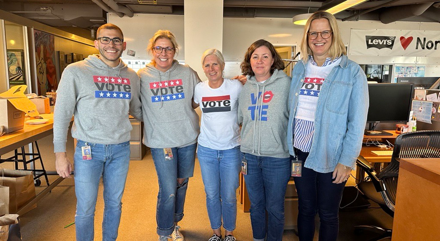 A group of five LS&Co. employees stand in an office and pose wearing 