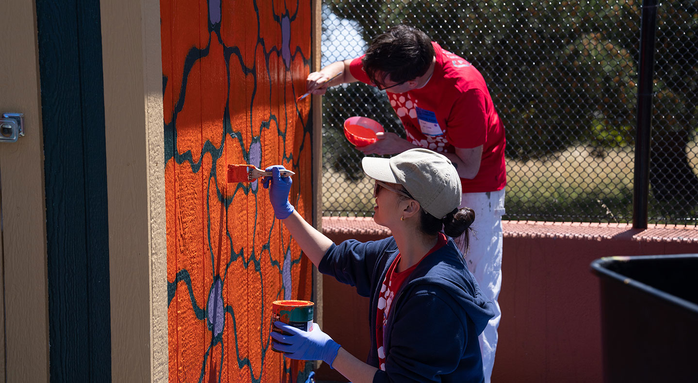 Two LS&Co. employee volunteers paint an orange and blue mural.