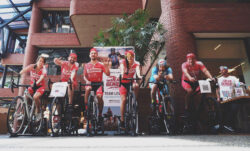 Six LS&Co. employees pose on stationary bikes wearing "Jean Genies" uniforms in the LS&Co. SF headquarters. 