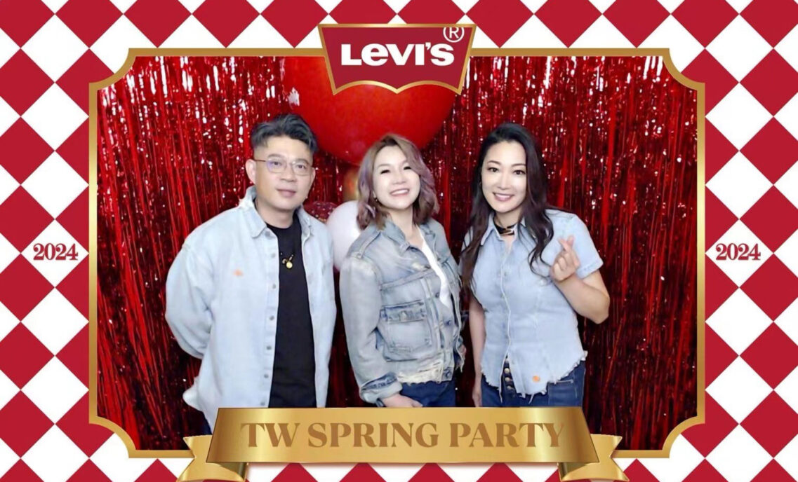 Christy Su, LS&Co.'s new general manager of Taiwan and Hong Kong, poses at a holiday party with two other LS&Co. employees in front of a shiny red streamer background. There is a designed red and white border around the photo featuring the Levi's® logo at the topand the words "TW Spring Party" on a gold rectangle at the bottom.