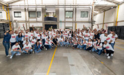 A large group of LS&Co. employees wearing matching white Colombia Levi's® T-shirts smile and pose.