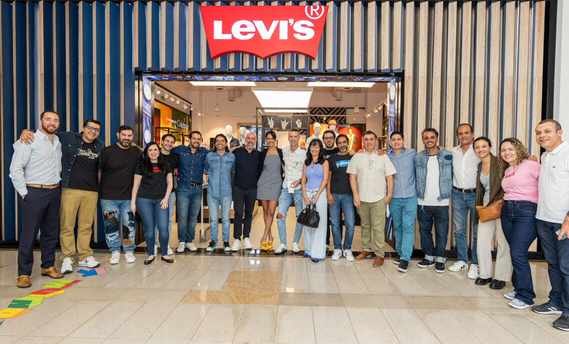 A group of 20 LS&Co. employees stand side by side and smile in front of a Levi's® store to celebrate the buy-back of Levi's® stores in Colombia.