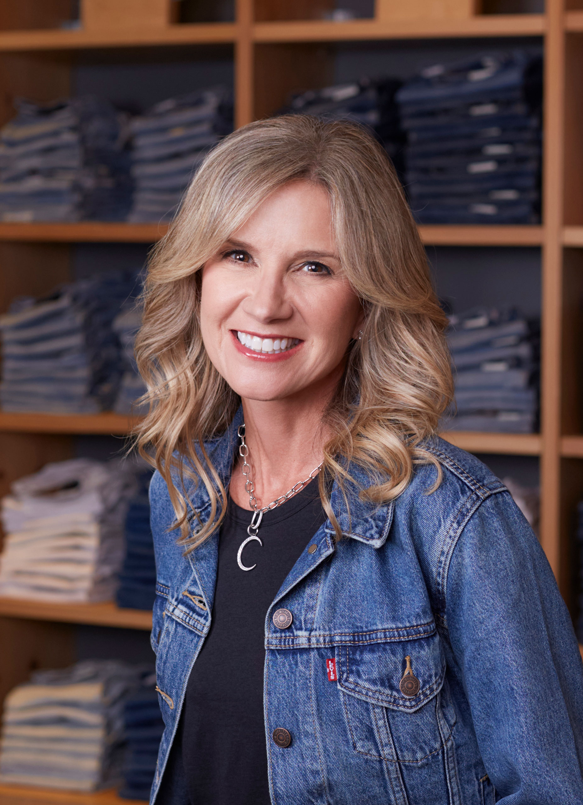 LS&Co. CEO Michelle Gass smiles in front of a wall of Levi's® denim jeans. She wears Levi's® Trucker jacket.