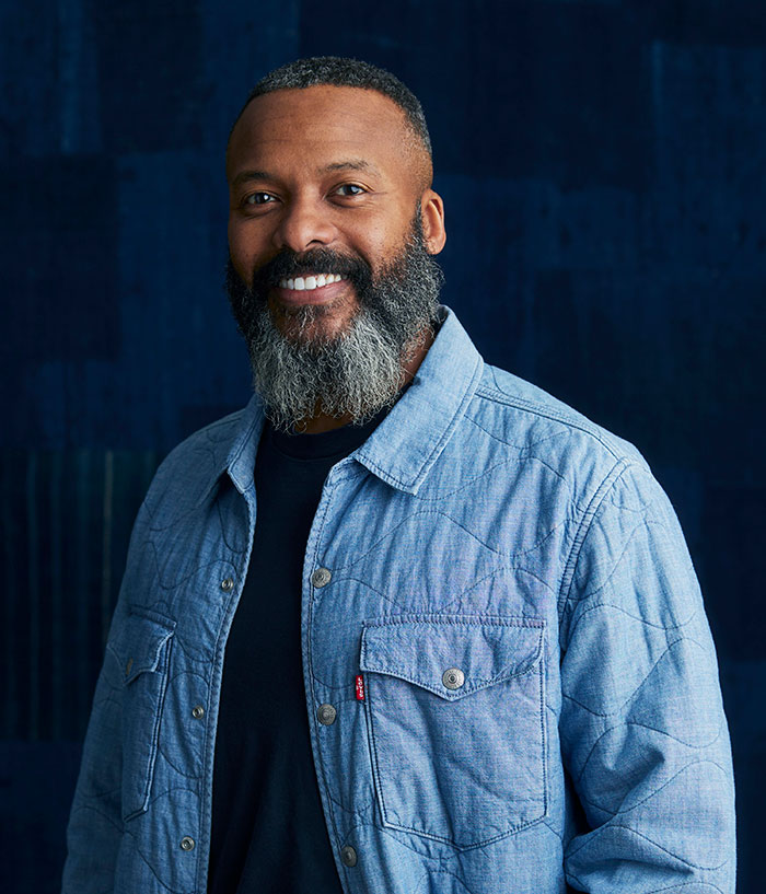 A headshot of LS&Co. CHRO Bernard Bedon in front of a dark blue texture background.
