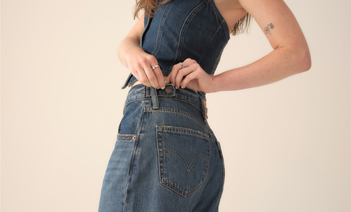 A person adjust the waistband on their Levi's® cinch baggy jeans