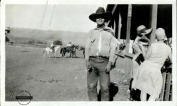 a black and white photo of 1928 Bucking Contest Winner Kenneth Cooper wearing Levi’s® cowboy gear in Hollywood, Colorado, standing next to two flappers with bobbed hair and short dresses.