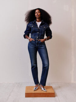 A model stands in front of a plain background on top of a wooden platform wearing a dark wash Levi's® denim jacket and matching Levi's® 501® curve jeans.