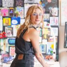 A photo of Holly Hapka wearing Levi's standing in front of a collage board looking over her shoulder. Behind the photo is a denim pattern background.