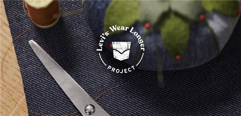 a white logo reading "Levi's® wear longer project" overlaid on top of an image of a piece of denim, sewing scissors and a denim pin cushion