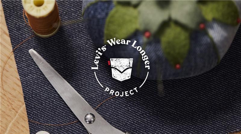a white logo reading "Levi's® wear longer project" overlaid on top of an image of a piece of denim, sewing scissors and a denim pin cushion