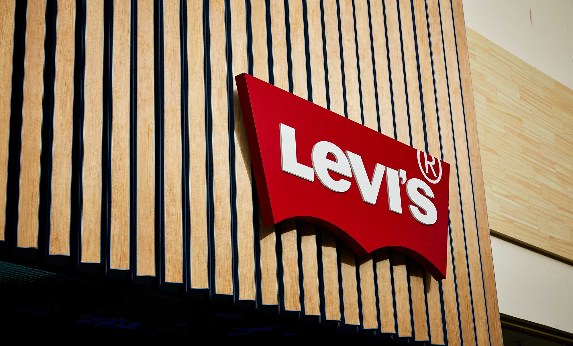 A cropped image of a Levi's® storefront, featuring the Levi's® batwing logo on top of wooden slats.