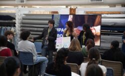 Three San Francisco high school students stand and present a poster board to a group of seated high school students as part of their "impact project" from a Levi's® Wear Longer Project workshop at the LS&Co. Eureka Innovation Lab
