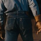 The backside of a person wearing Levi's® dark was denim jeans with a long sleeve light blue shirt