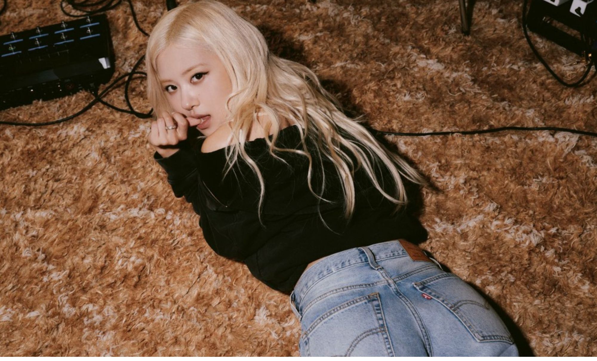 Rosé lying on her stomach looking over her shoulder while wearing Levi's jeans