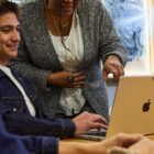 A Levi Strauss & Co. employee sits at a table looking at their laptop as another employee points to their screen