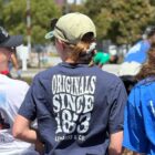 A Gap employee, an LS&Co. employee and KPMG employee stand with their backs to the camera wearing their company volunteer shirts at a Downtown Volunteer Coalition volunteer project