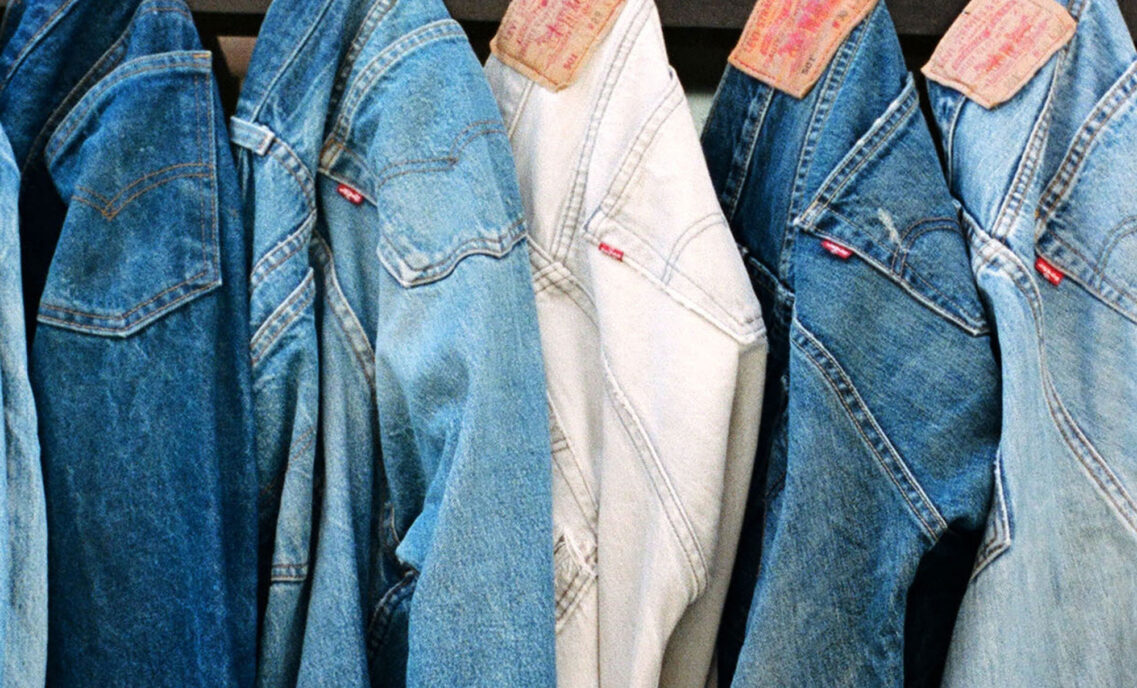 Five pairs of Levi's® 501® jeans in various washes of blue hang in a line by the back beltloop.