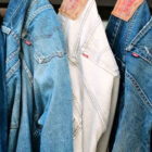 Five pairs of Levi's® 501® jeans in various washes of blue hang in a line by the back beltloop.