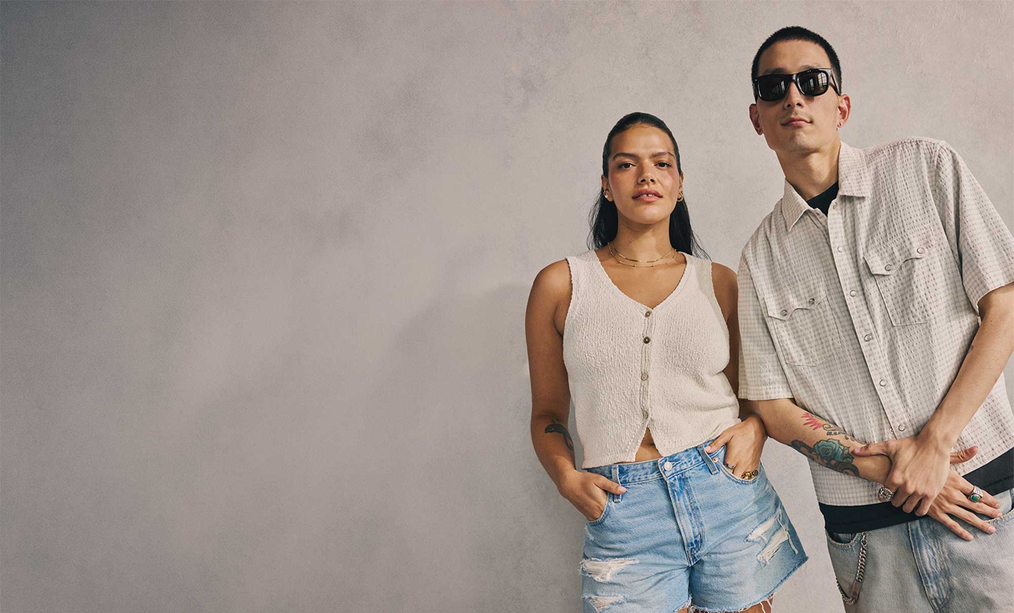 Two models wearing Levi's® summer product lean against a grey backdrop