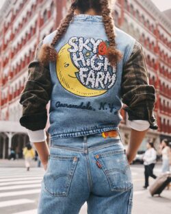 A campaign image from the Levi's® x Sky High collaboration, featuring a person standing with their back to the camera wearing Levi's® jeans and a Levi's® x Sky High jacket featuring a Sky High Farm logo with a moon and strawberry design.