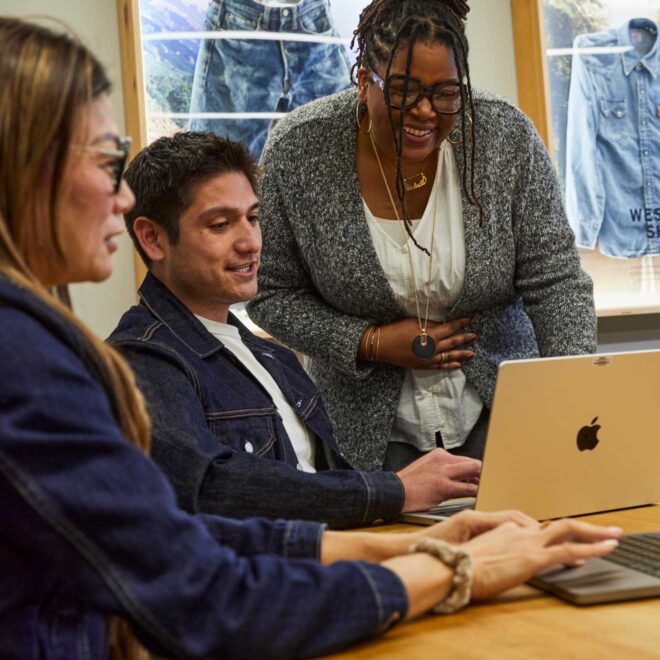 Three LS&Co. employees gather around a laptop at a meeting