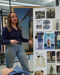 A Levi Strauss & Co. employee wearing a dark blue long sleeve shirt tucked into light wash Levi's® denim jeans stands in front of a presentation board featuring images of Levi's® product