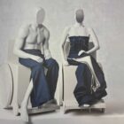 Two pale grey mannequins in wheelchairs wear denim Levi's outfits against a grey backdrop as part of The Met’s “Costume Art” exhibit