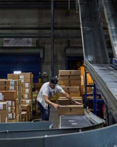 A Levi's® distribution center employee loads a cardboard box onto a conveyer belt