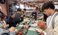 A group of San Francisco high school students gather around a large table with sewing supplies and print out sewing tutorials at a Levi's Wear Longer Project workshop