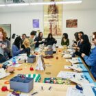 A group of San Francisco high school students gather around a large table with sewing supplies and print out sewing tutorials at a Levi's Wear Longer Project workshop