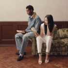 Two people pose on a couch reading books wearing Levi's® outfits
